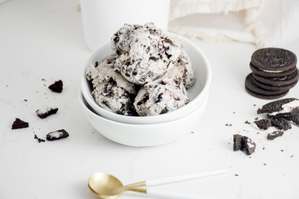 Cookies 'n Cream Ice Cream Scoops in a white bowl on a white background with crumbles cookies on either side