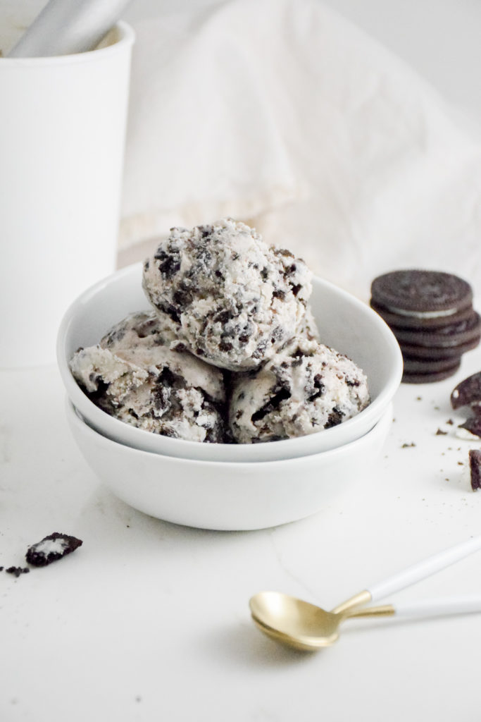 Cookies 'n Cream Ice Cream Scoops in a white bowl on a white background with crumbles cookies on either side