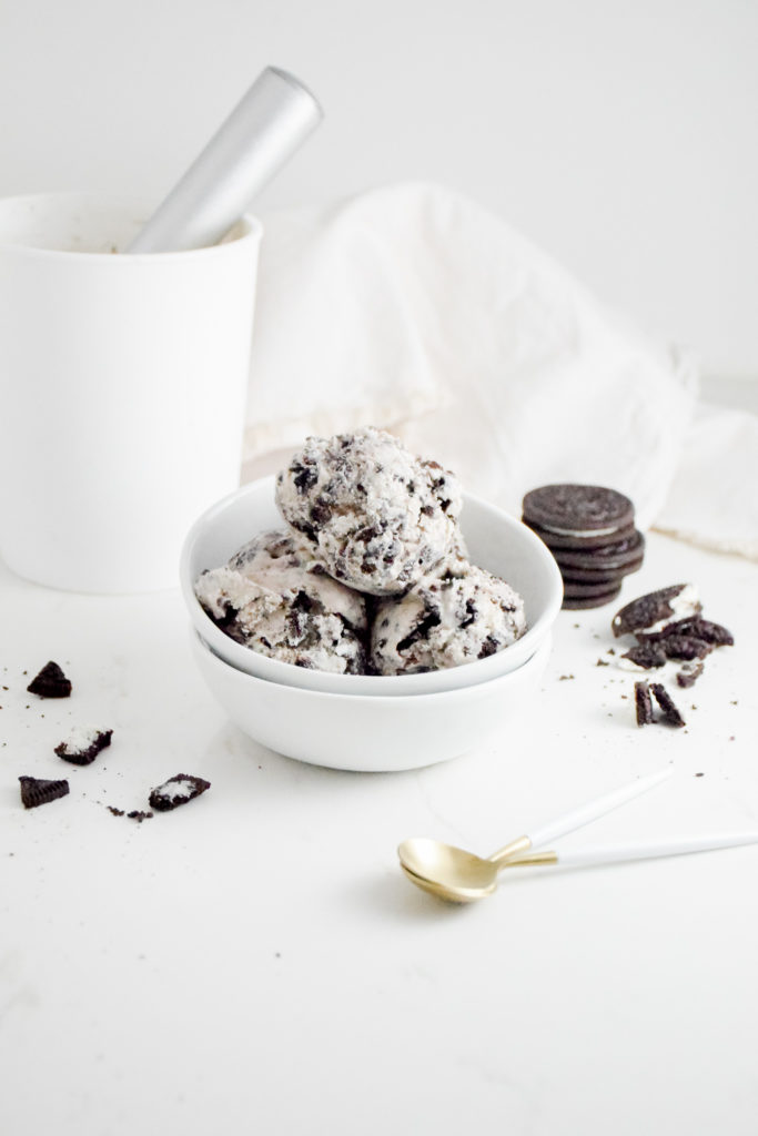 Cookies 'n Cream Ice Cream Scoops in a white bowl on a white background with crumbles cookies on either side