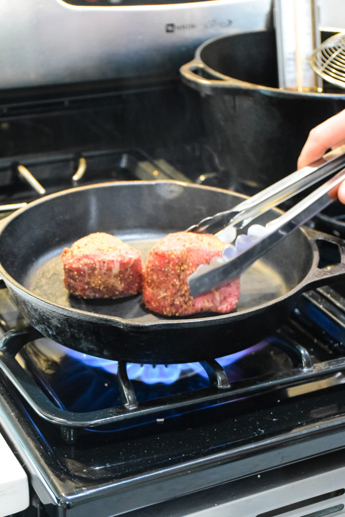 Steak filtes cooking in a cast iron skillet