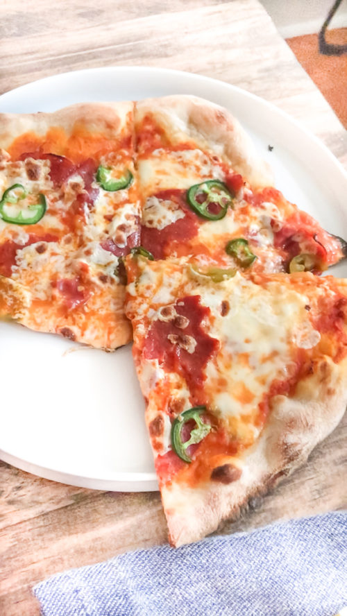 Pizza with green peppers on a white plate