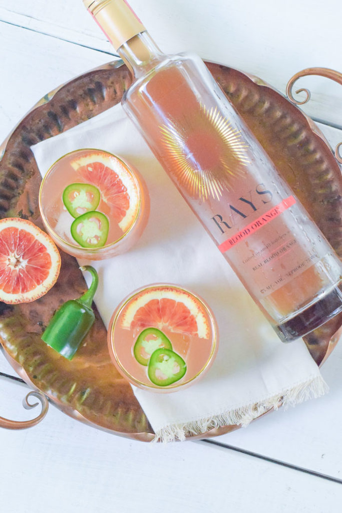 overhead photo of blood orange cocktail with thin slices of jalapeño and bottle of Rays Spirits flavor blood orange