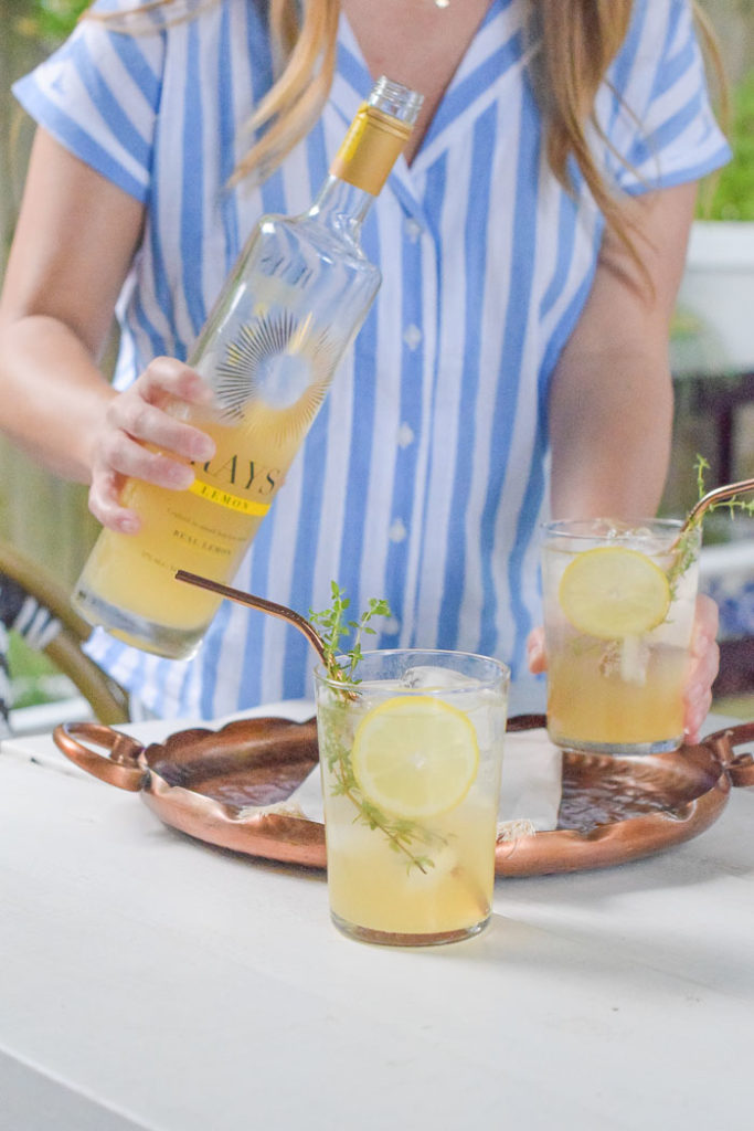 woman in striped blue and white shirt pouring lemonade cocktails 